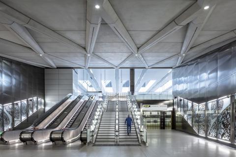 View of man walking upstairs next to escalator at Farringdon Station.